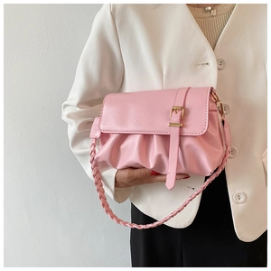 Pink pleated leather shoulder bag with woven strap and gold buckle on casual blazer