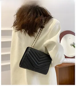 Detail of a black quilted crossbody bag with a gold-and-black interwoven chain strap