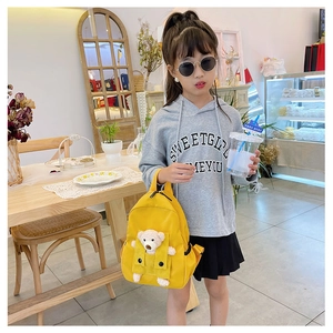 Dettaglio di zainetto giallo per bambini con orsetto di peluche 3D e gilet a quadretti