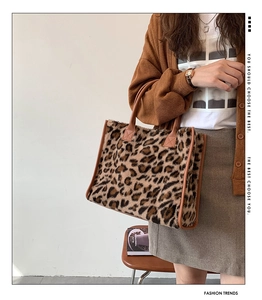 Detail of plush leopard print tote bag featuring brown faux leather handles and piping