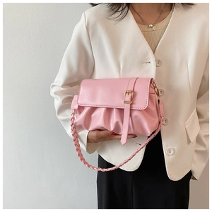 Detail of pink pleated crossbody bag with belt buckle and woven shoulder strap on model