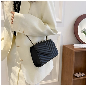 Close-up of black quilted leather crossbody bag with elegant gold chain shoulder strap