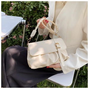 Detail view of beige ruched shoulder bag with woven handle and gold buckle decoration