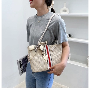 Detail of straw woven tote with floral silk scarf and rope shoulder strap for summer vacation