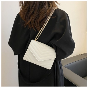 Rear view of model wearing a white quilted crossbody bag with a gold chain strap