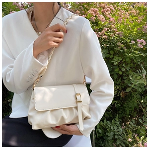 Detail of a creamy white pleated cloud bag with woven strap and gold buckle