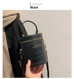 Details der schwarzen Zylindertasche mit Krokostruktur, Goldzipper und Schriftzug