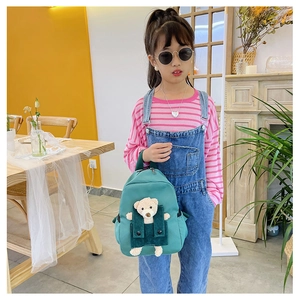 Dettaglio zaino verde per bambini con orsetto di peluche 3D indossato dalla bimba