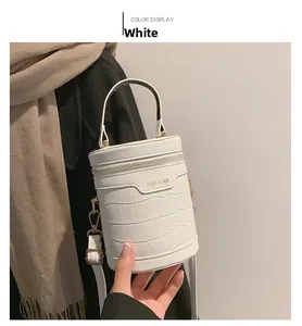 Detail der weißen Beuteltasche mit Krokoprägung, Goldverzierung und verstellbarem Riemen