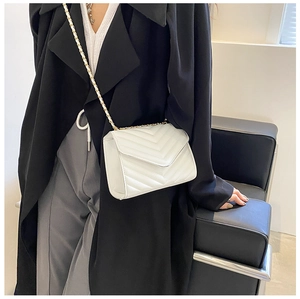 Detailed view of white quilted crossbody bag with gold chain strap and envelope flap design