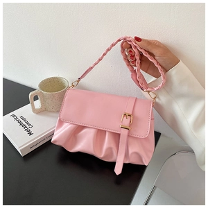 Detail of pink pleated shoulder bag featuring a woven strap and gold buckle accent