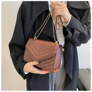 Detail view of brown V-quilted leather crossbody bag with gold chain shoulder strap