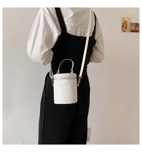 Detailansicht der weißen Zylindertasche mit Krokodilmuster und goldenem Reißverschluss