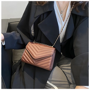 Detail of V-quilted texture and gold chain strap on a dark brown envelope bag