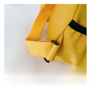 Dettaglio dello zaino in nylon giallo con cuciture robuste e fibbia di regolazione in plastica nera