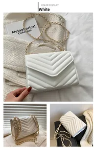 Close-up of white quilted leather bag with V-shaped stitching and gold chain strap