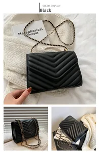 Detail of black quilted shoulder bag with V-shaped stitching and golden chain strap