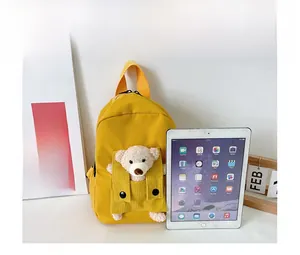 Zaino giallo per bambini con orsetto e confronto dimensioni accanto a un iPad