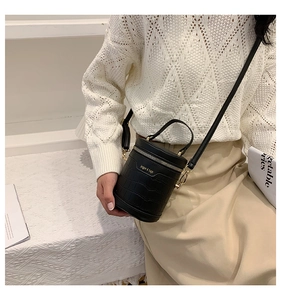 Detail der schwarzen Zylindertasche mit Krokoprägung und goldenen Beschlägen im Lifestyle-Look