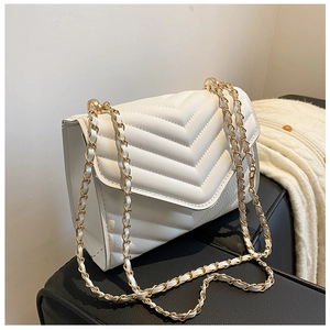 Detail of white quilted handbag featuring gold metal chain strap and V-pattern texture