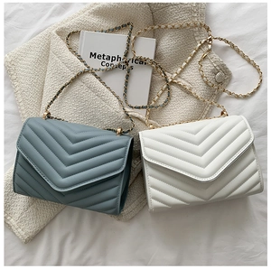 Detail of blue and white envelope bags with V-shaped quilting and golden chain straps