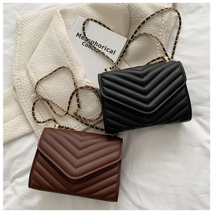 Detail view of V-quilted faux leather crossbody bags in black and vintage brown colors