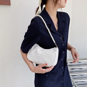White floral lace baguette bag with pearl shoulder strap carried by a model
