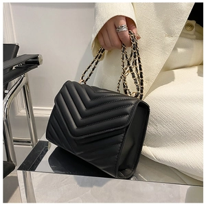 Close-up of black quilted leather shoulder bag featuring elegant V-stitch detail and chain