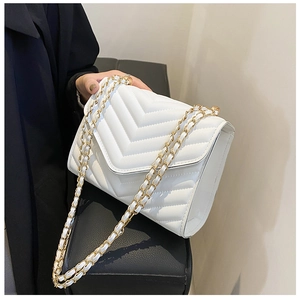 Detail of white V-quilted faux leather crossbody bag with elegant gold chain strap