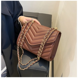 Detailed view of brown chevron quilted flap bag with golden metal chain shoulder strap