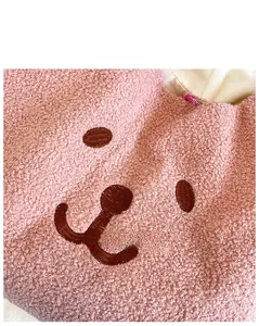 Détail du tissu en laine d'agneau rose avec motif visage d'ours brodé à la main sur le sac