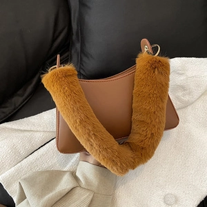 Detail of a brown shoulder bag with a thick faux fur handle and durable metal hardware hooks