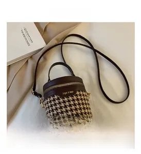 Close-up of mini cylinder bag featuring houndstooth pattern and brown leather trim