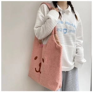 Gros plan d'un sac cabas en peluche rose avec broderie ours sur un mannequin femme