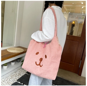 Gros plan du sac fourre-tout rose en peluche avec broderie d'ours dans un cadre doux
