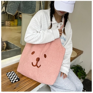 Sac cabas en polaire rose avec broderie ours porté à l'épaule par un mannequin en pose