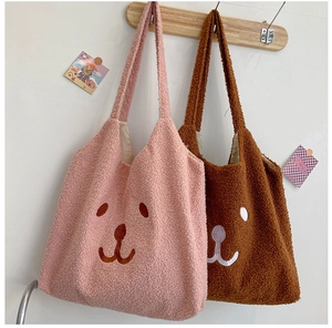 Détail de sacs fourre-tout ours en peluche rose et marron sur patère en bois