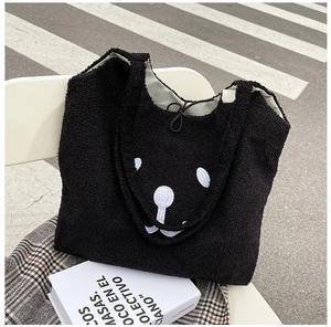 Détail d'un sac cabas noir en polaire avec motif ours blanc sur un siège extérieur