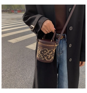 Detail of leopard print cylinder bag with leather trim and adjustable shoulder strap