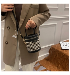 Close-up of a mini houndstooth bucket bag with leather trim and golden zipper detail
