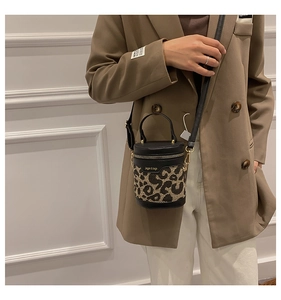 Detail of a mini leopard print bucket bag with leather trim and shoulder strap on model