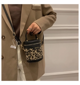 Detail of leopard print cylinder bag with gold zipper and black leather trim