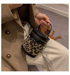 Detail of leopard print cylinder bucket bag with black leather handle and gold hardware