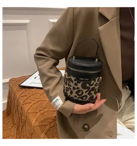 Detailed view of leopard print bucket bag with black leather handle and metal zipper