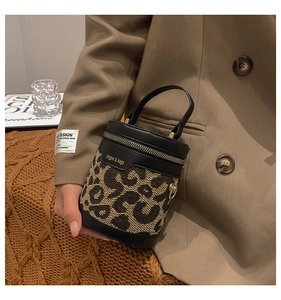 Detailed close-up of leopard print bucket bag with leather trim and metallic zipper details