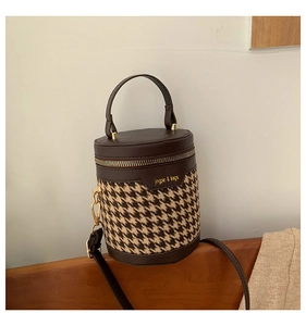 Top view of houndstooth cylinder bucket bag with leather handle and gold hardware detail