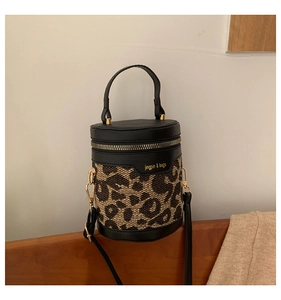 Detailed view of leopard print bucket bag with black leather trim and golden hardware