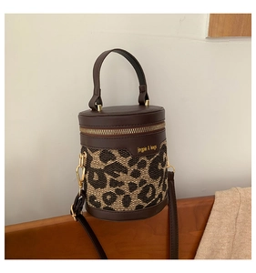 Detail view of leopard print bucket bag with leather trim on a vintage wooden bench