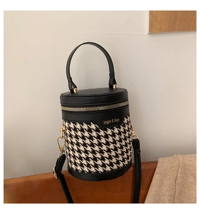 Macro view of houndstooth weave fabric and gold metal zipper on cylindrical bucket bag