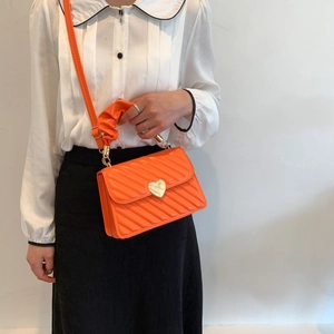 Detail der orangefarbenen Stepptasche aus PU-Leder mit Herzschließe und Falten-Tragegriff